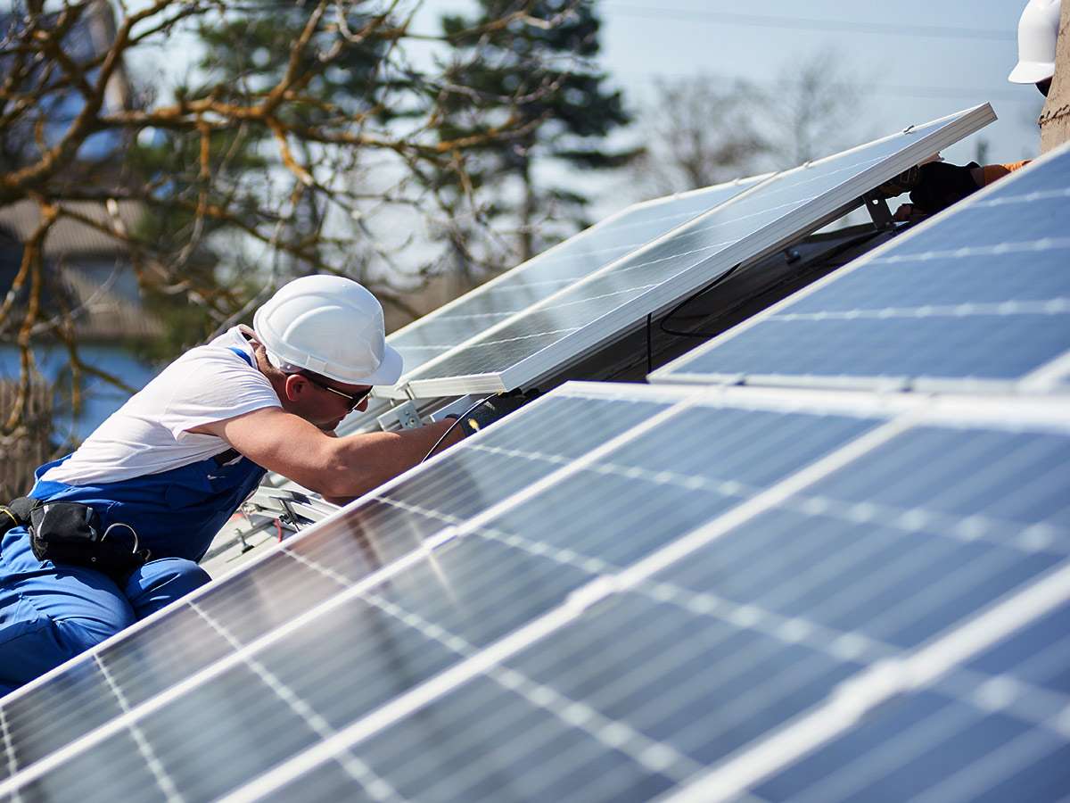 Two LH Electrical installers fitting solar panels on a house roof